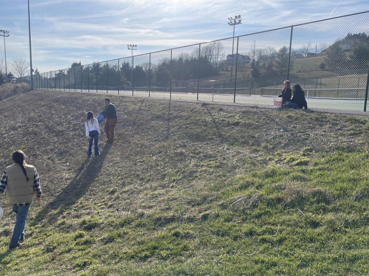 Issac Matlock helping students with spreading the seeds.