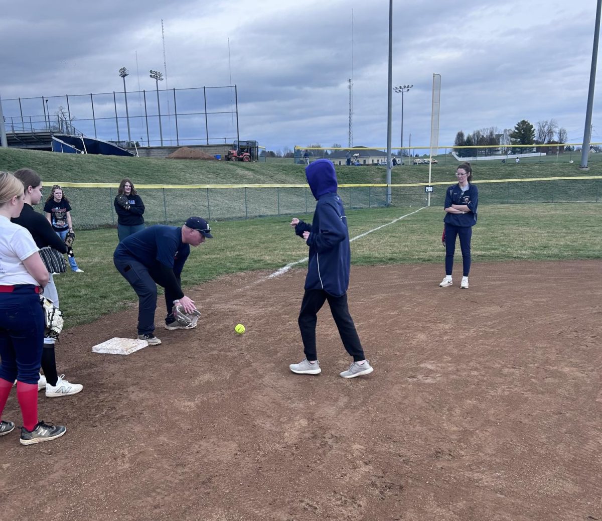 Head varsity coach Derek Smiley assists by showing the JV players how to catch a ball and make the tag.