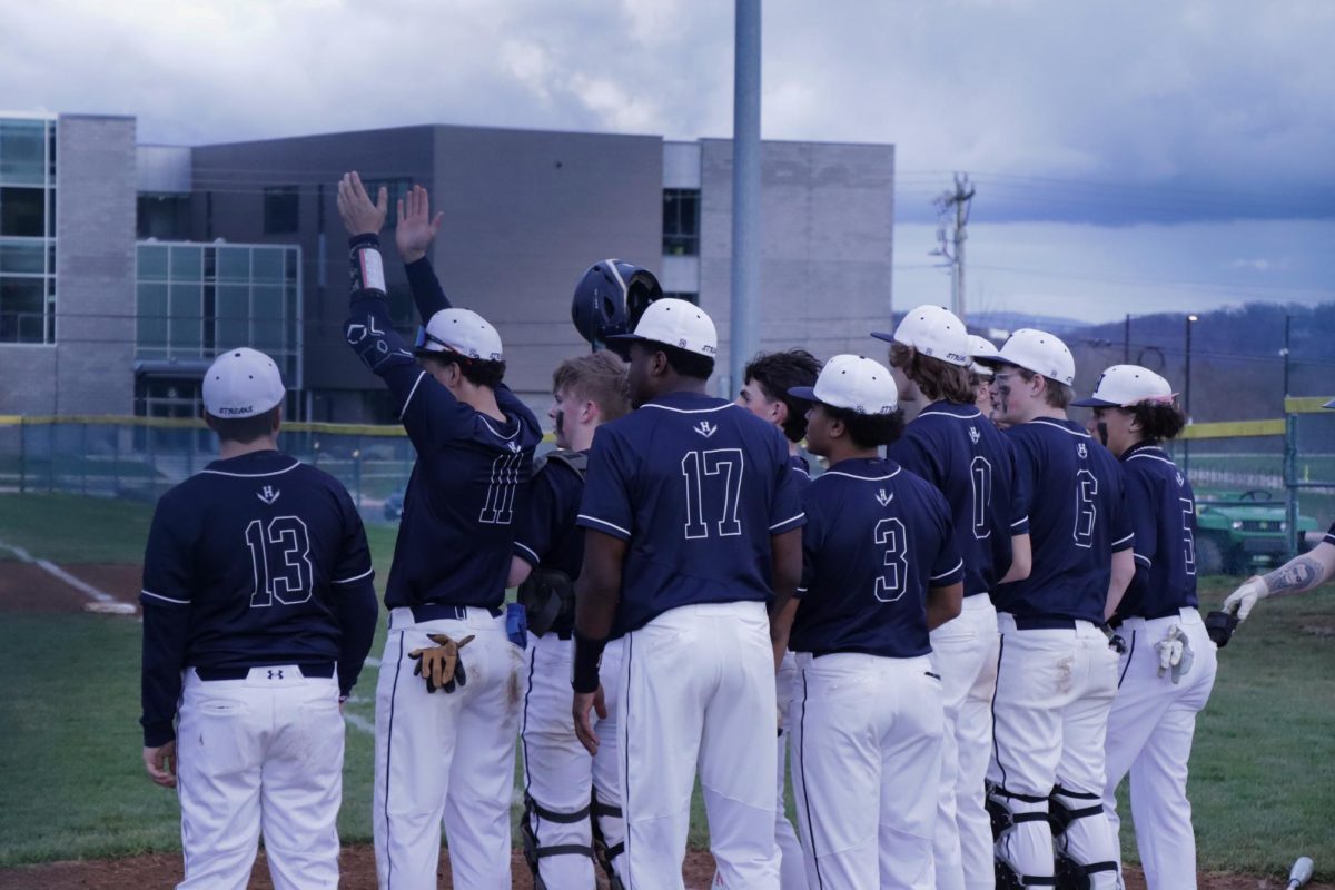 The varsity baseball team huddle together after getting a run.