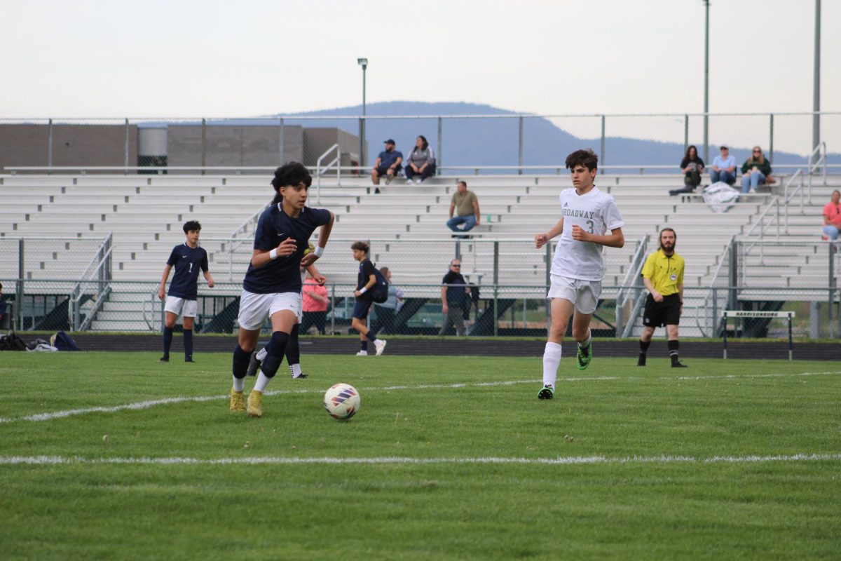 Freshman Dani Ayala dribbling up the field with a defender tracking backing.