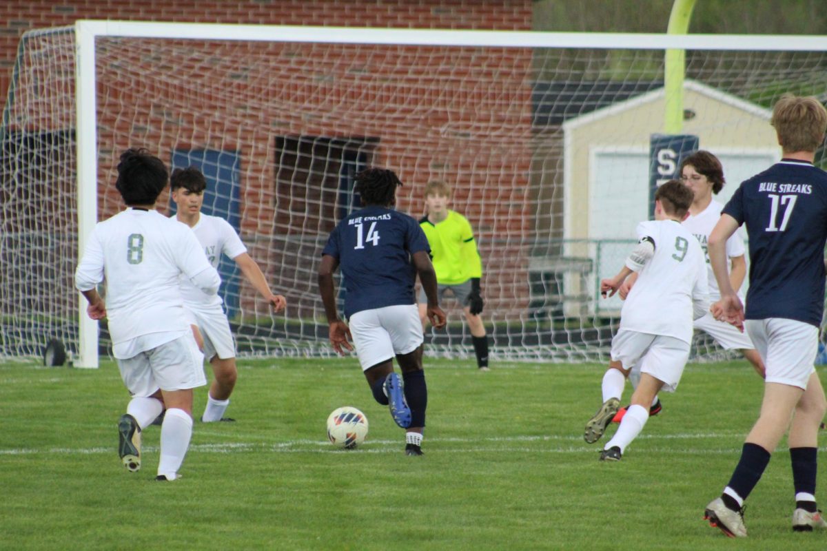 Sophomore Michael Bayongwa dribbles towards the box with multiple defenders around.