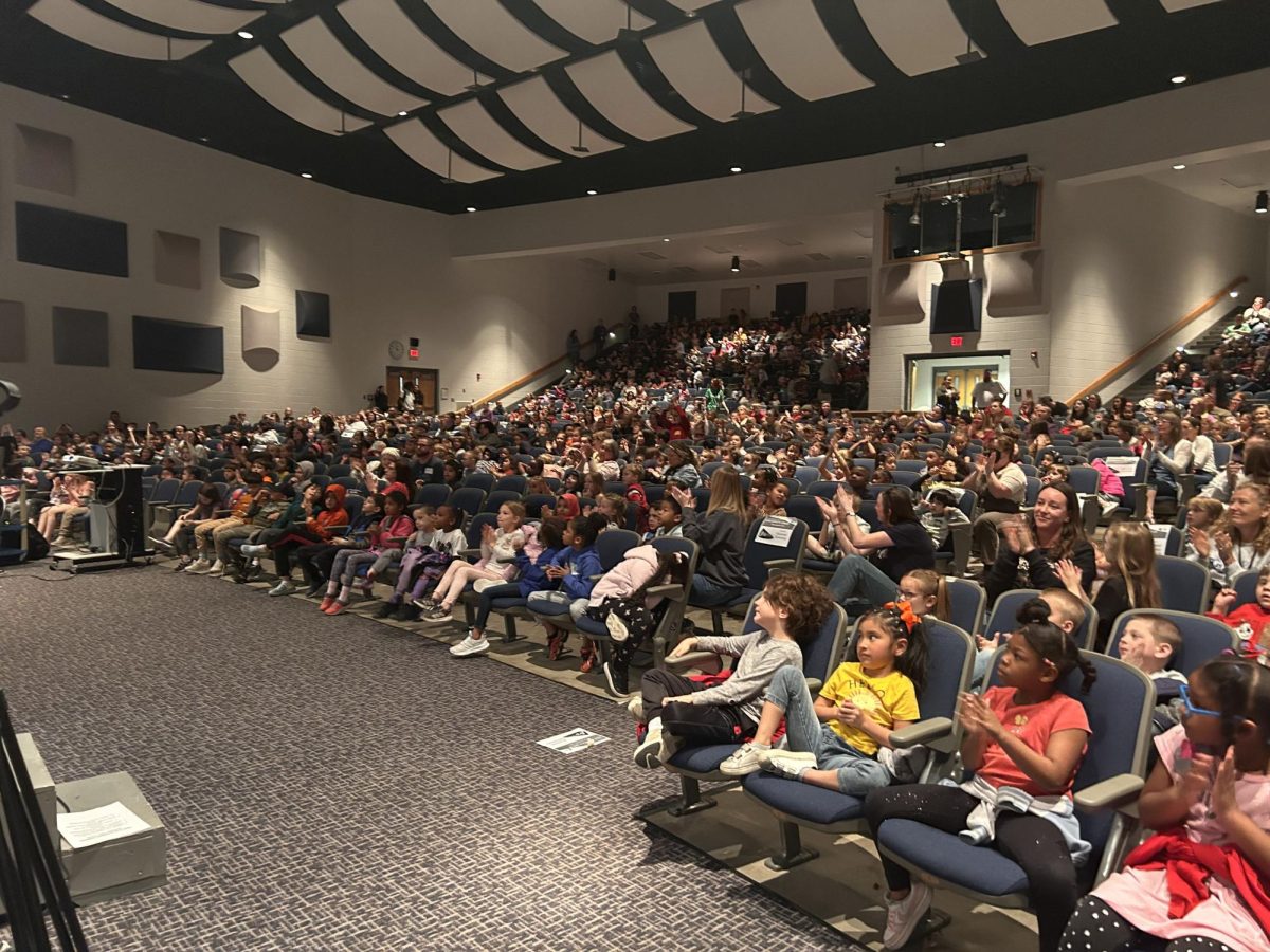 Elementary students sit in auditorium to watch Tiny Tots.  
