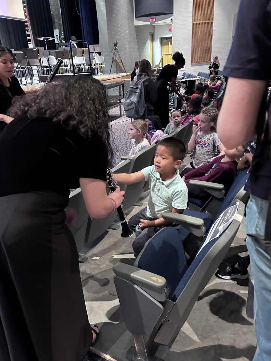 Sophomore Julemily Ayala-Chavez shows her instrument to visiting elementary schoolers after the show.
