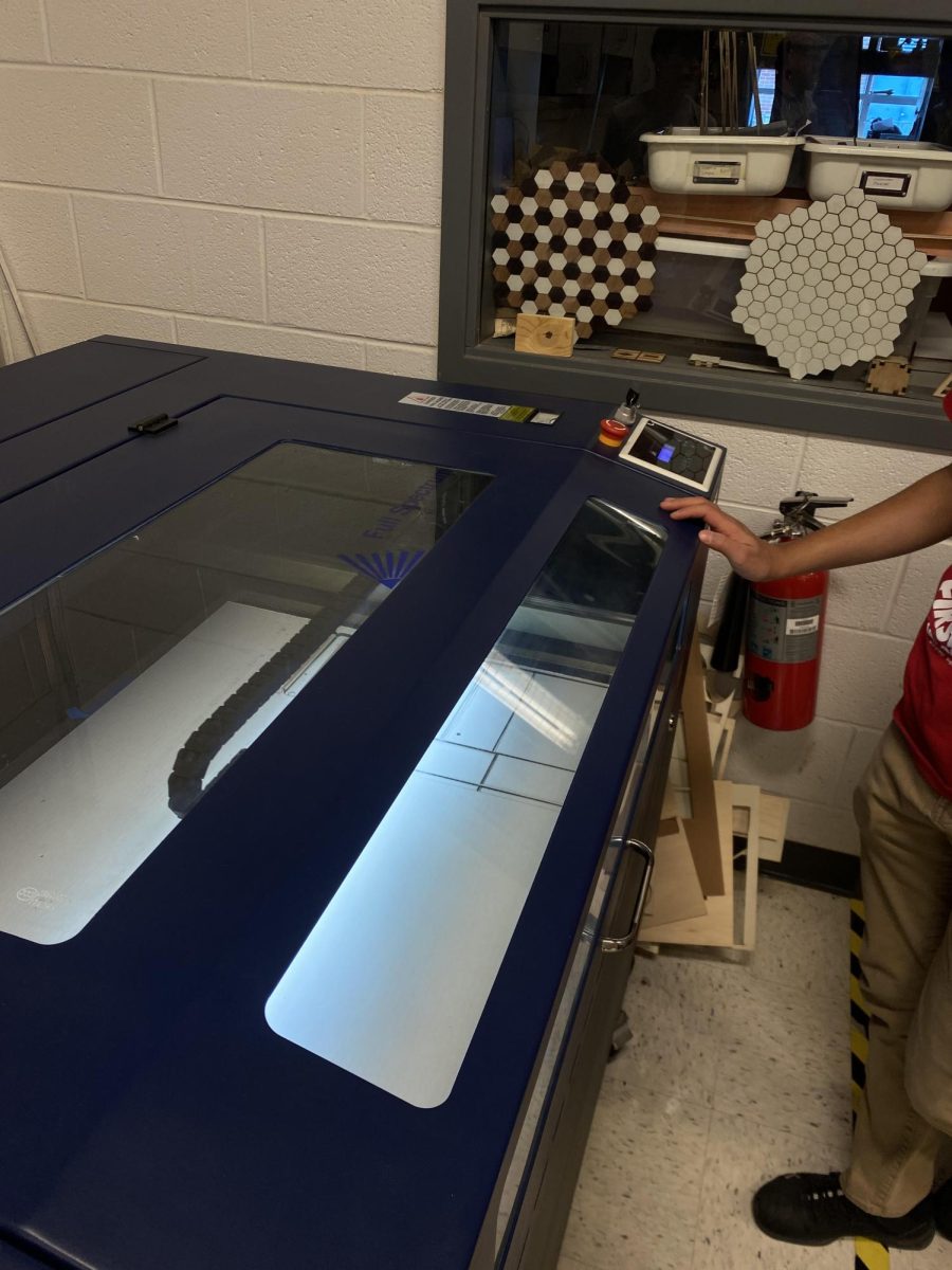 Innovation student laser cuts a piece of cardboard for a project.