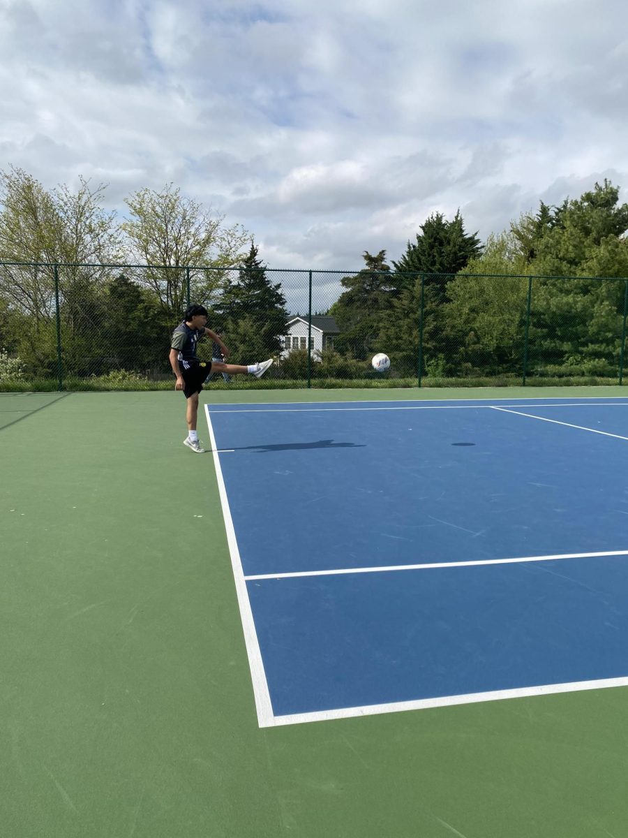 Freshman hits the soccer over the tennis net in a game of tennis soccer