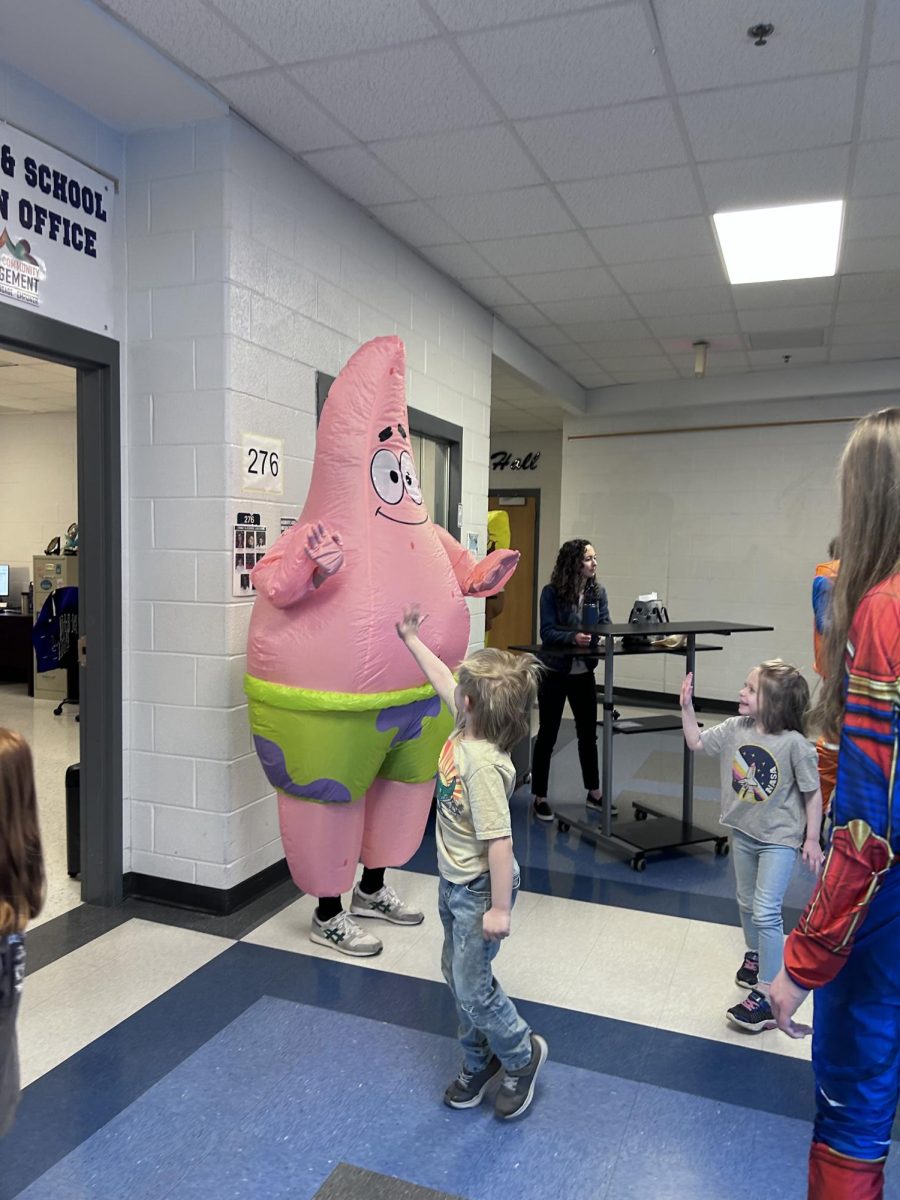 A band student dressed up as Patrick Star waves goodbye to the children as they leave.