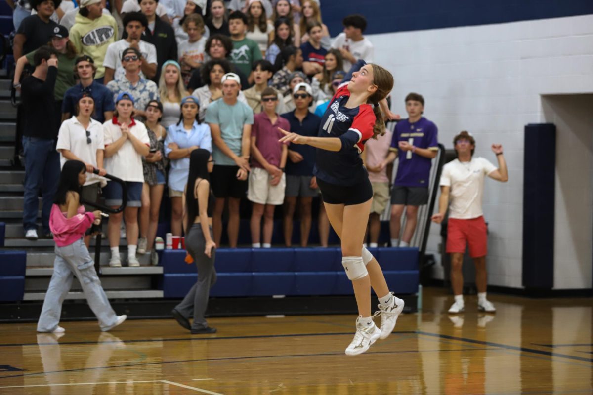 Freshman Maren Bert serves in first home volleyball game.