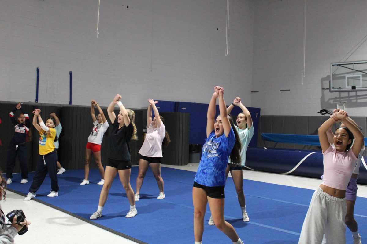 Jv sideline cheerleaders practicing motions for a football game.