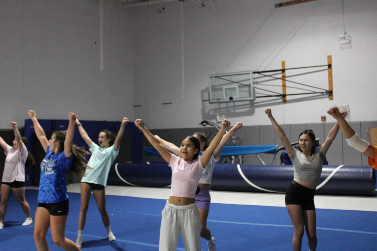 Jv sideline cheerleaders hitting a high V in one of the cheers.