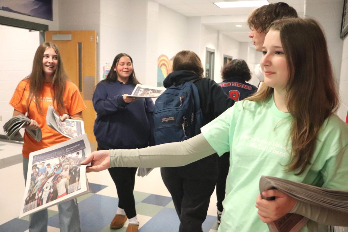 Seidal passes out the first issue of newspaper.