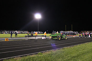 Sideline cheerleaders standing while Football players are together.