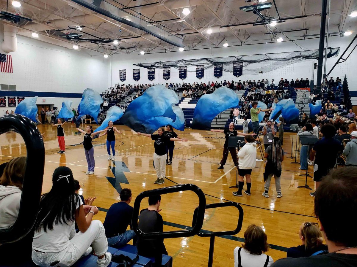 Color guard flips their colorful flags, featuring t=different shades of blue.