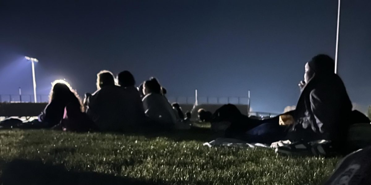 On the first of november students sat on the field and ate snacks. People joined together to enjoy the Barbie movie.