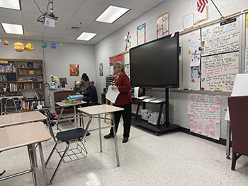 The teacher is speaking to the class. Giving out instructions on what to do next.