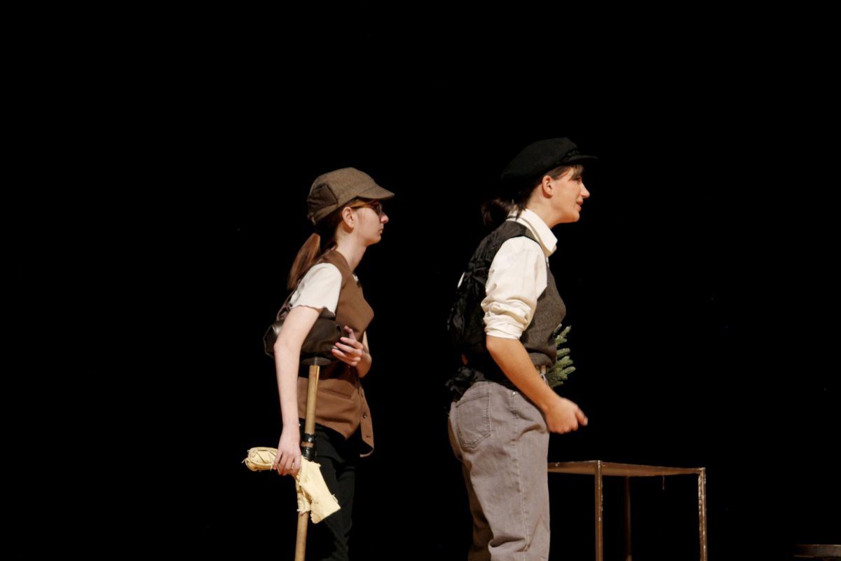 Bob Cratchit (Lila Hostetler) and his son Timmy (Jo Greathead) walk on stage.