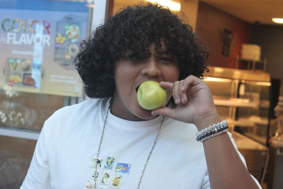 A kid eats a apple from the lunch room