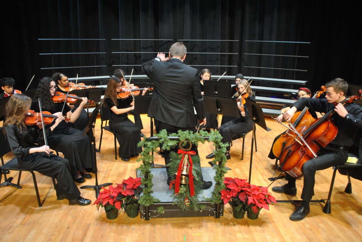 Mr Inchek leading the orchestra during their winter concert with a holiday spirit.