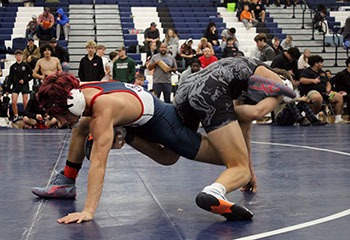 Wrestler Izaack Cruz holding the leg of his opponent.