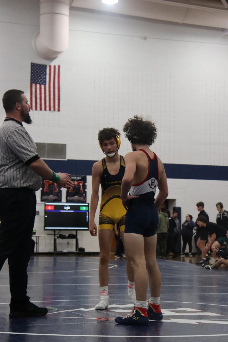 Mason George and his opponent listening to the referee talk. 