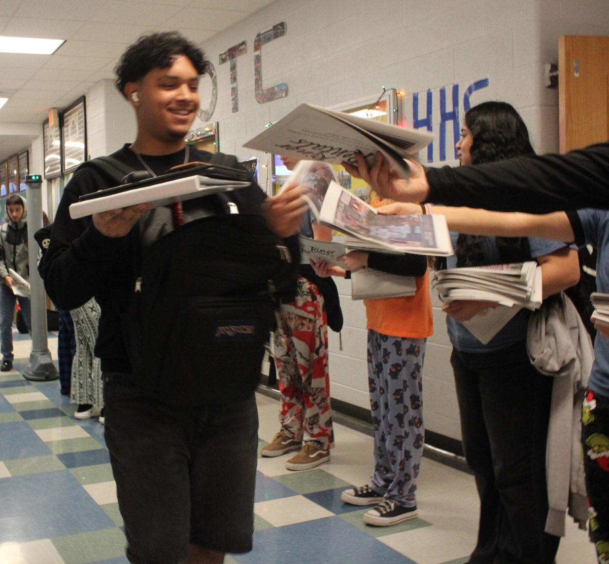 Broadcasting and Yearbook staff handing out newpapers to HHS student