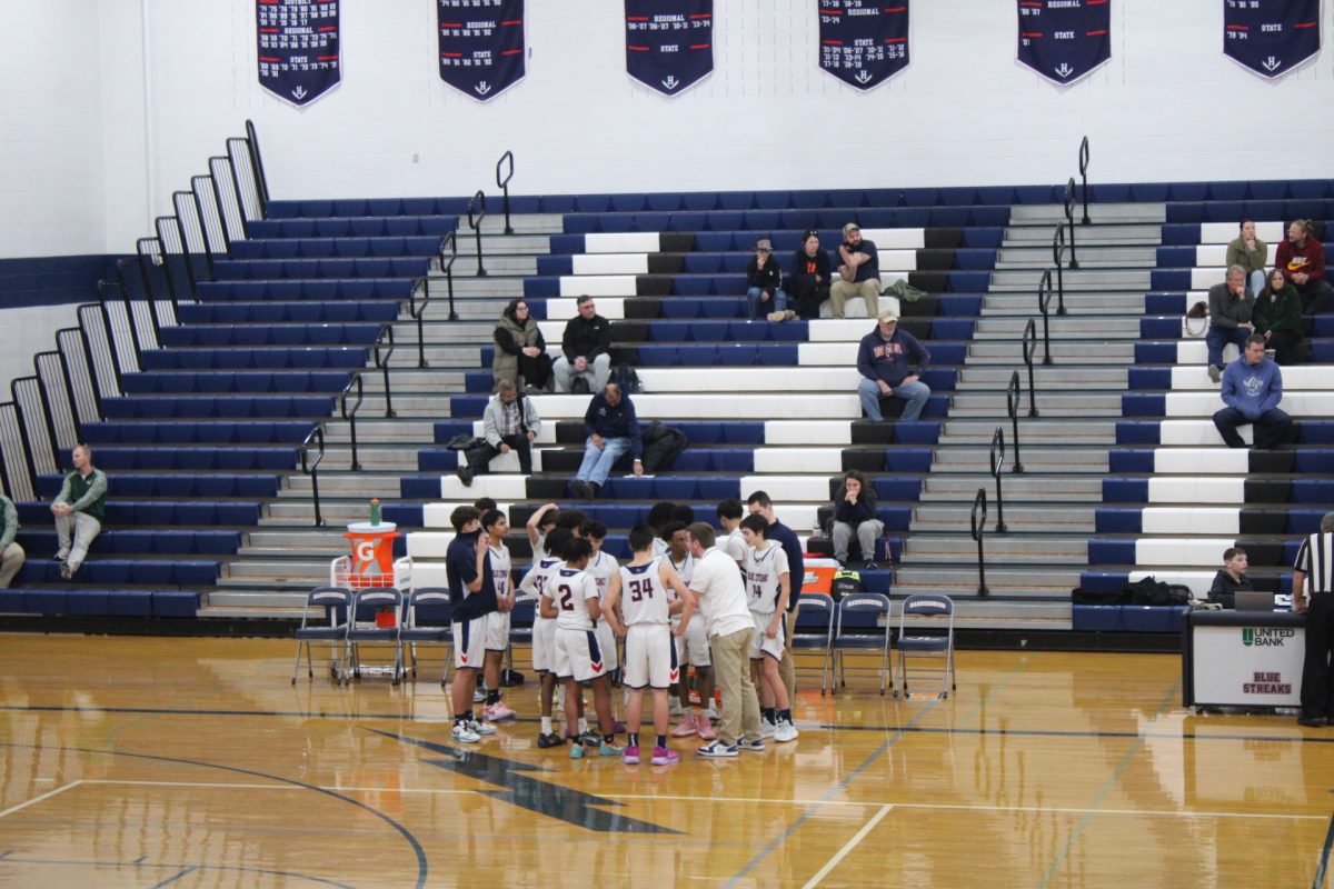 The Harrisonburg High School Junior Varsity boys basketball team huddles in a group. The team takes the time to go over a plan before heading onto the court.