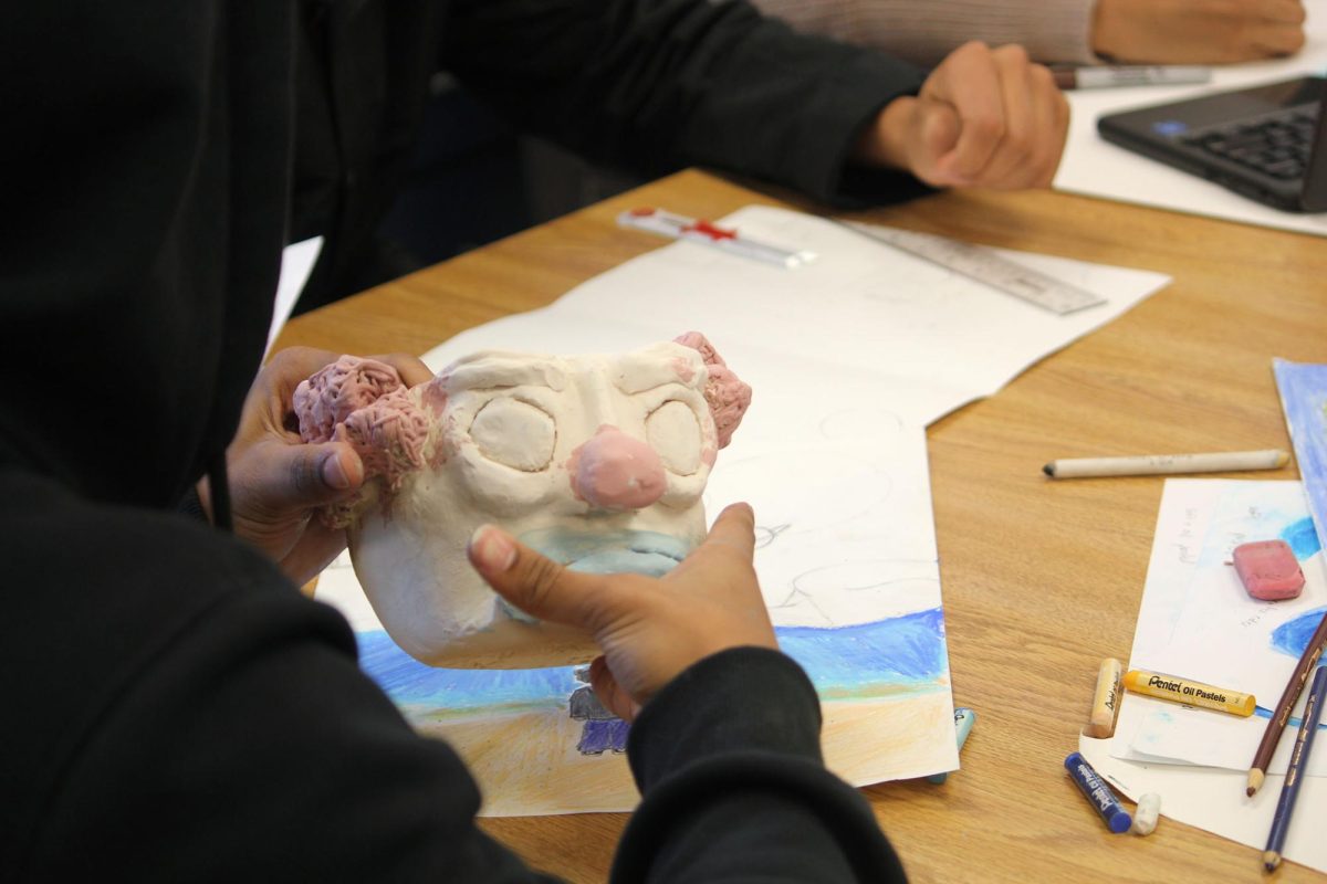 Student puts final touches on face mug.