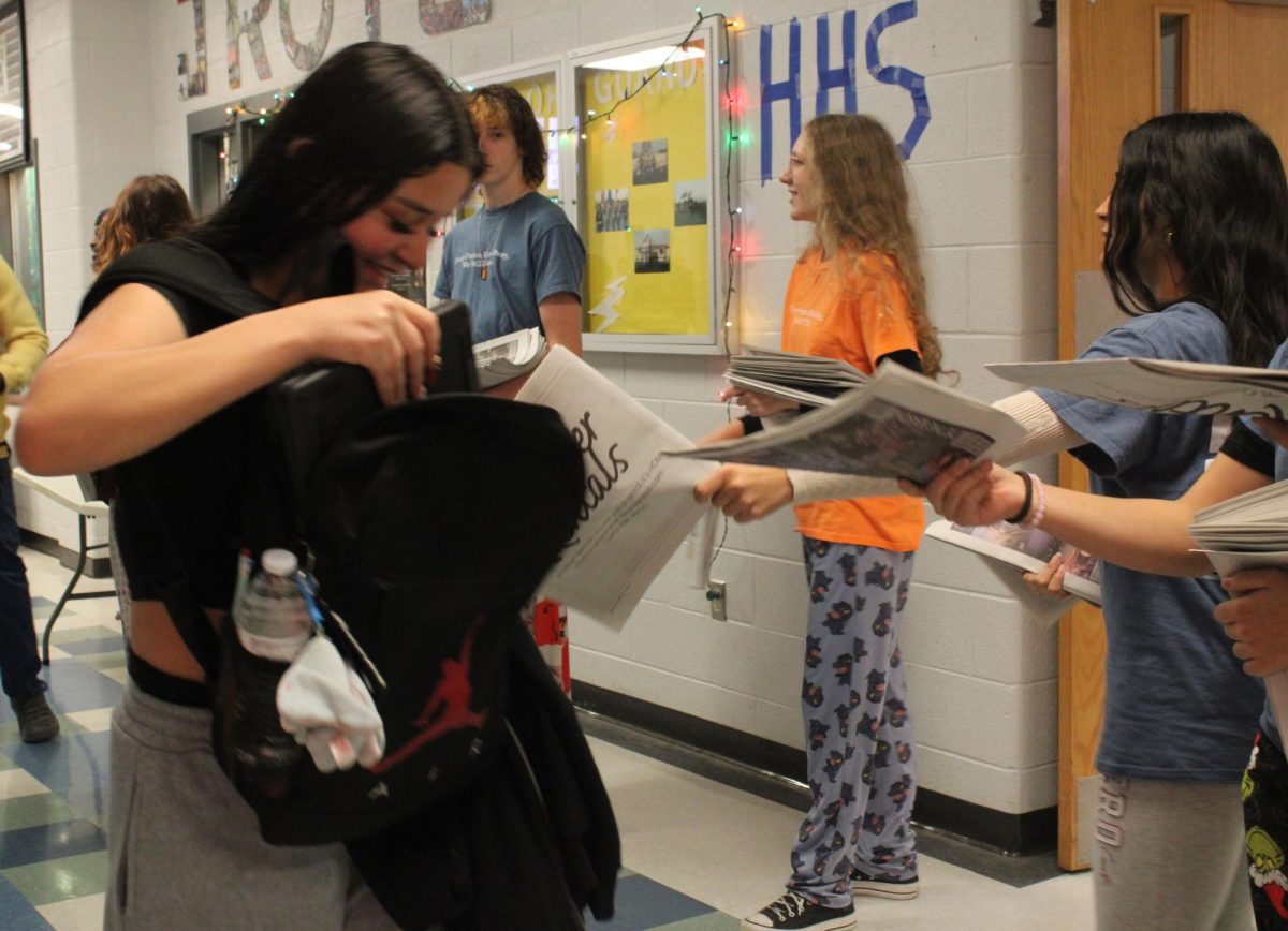 Multiple Staff handing out newspapers to HHS student