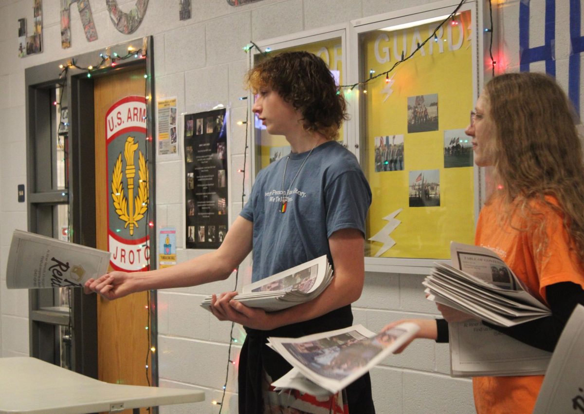 Broadcasting and Yearbook staff members working together to pass out newspapers