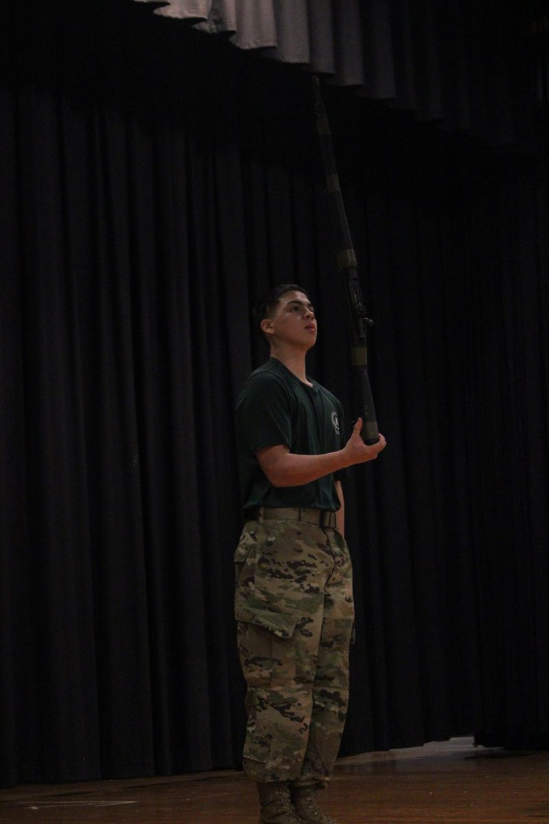Tano munguia holds rifle with on hang by the tip as he performs his spin routine.