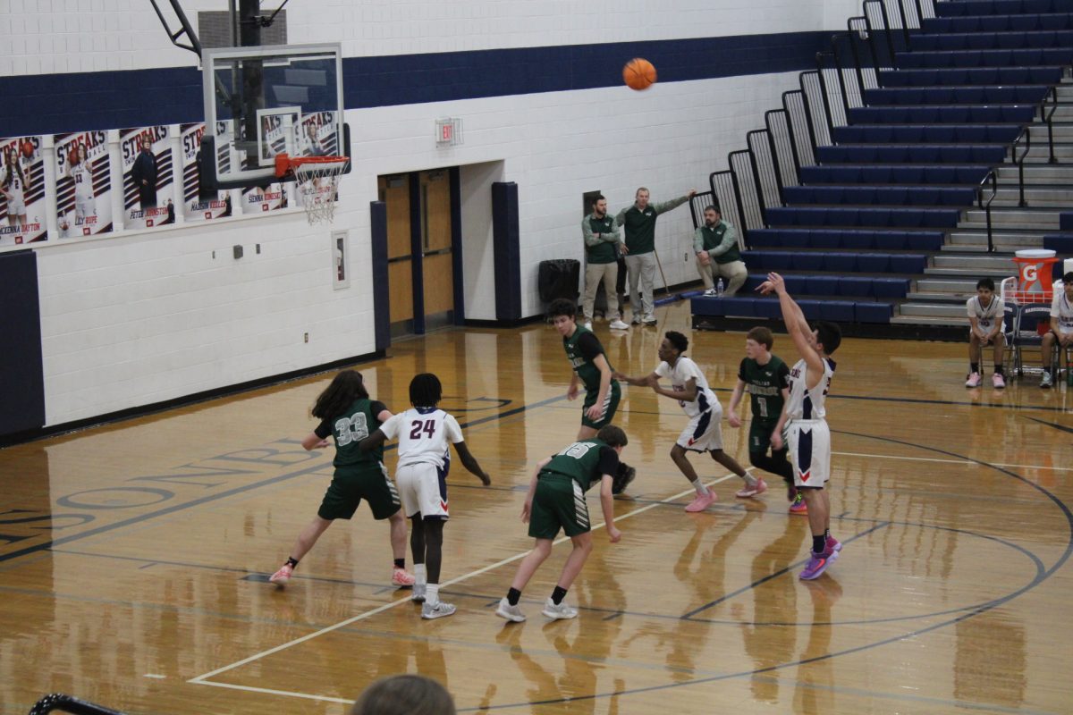 As the Harrisonburg High School basketball team shoots a free throw, the opposing team prepares to steal back the ball. The HHS basketball team goes into position to figure out the rebound.
