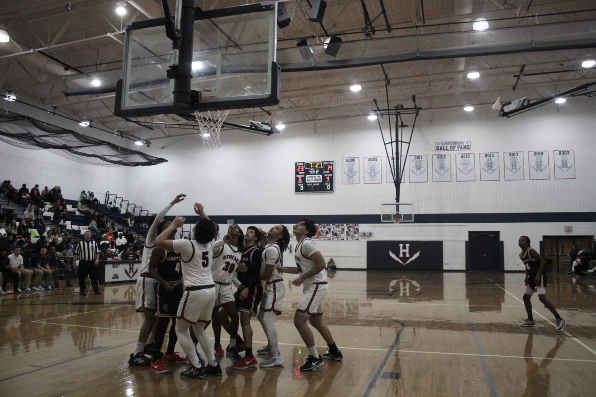The basketball team wait and stare at the basketball hoop to see the ball go in