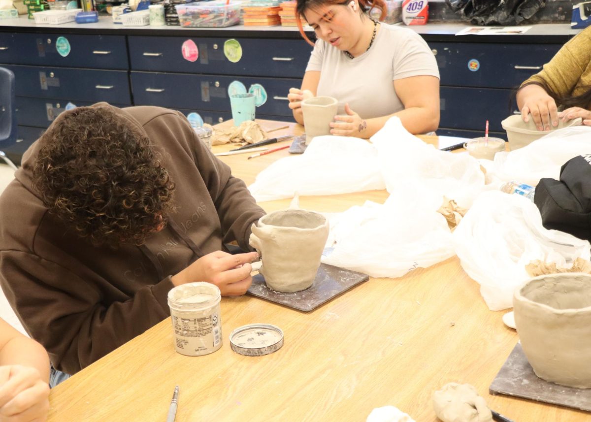Students focusing on their pottery projects in art class.