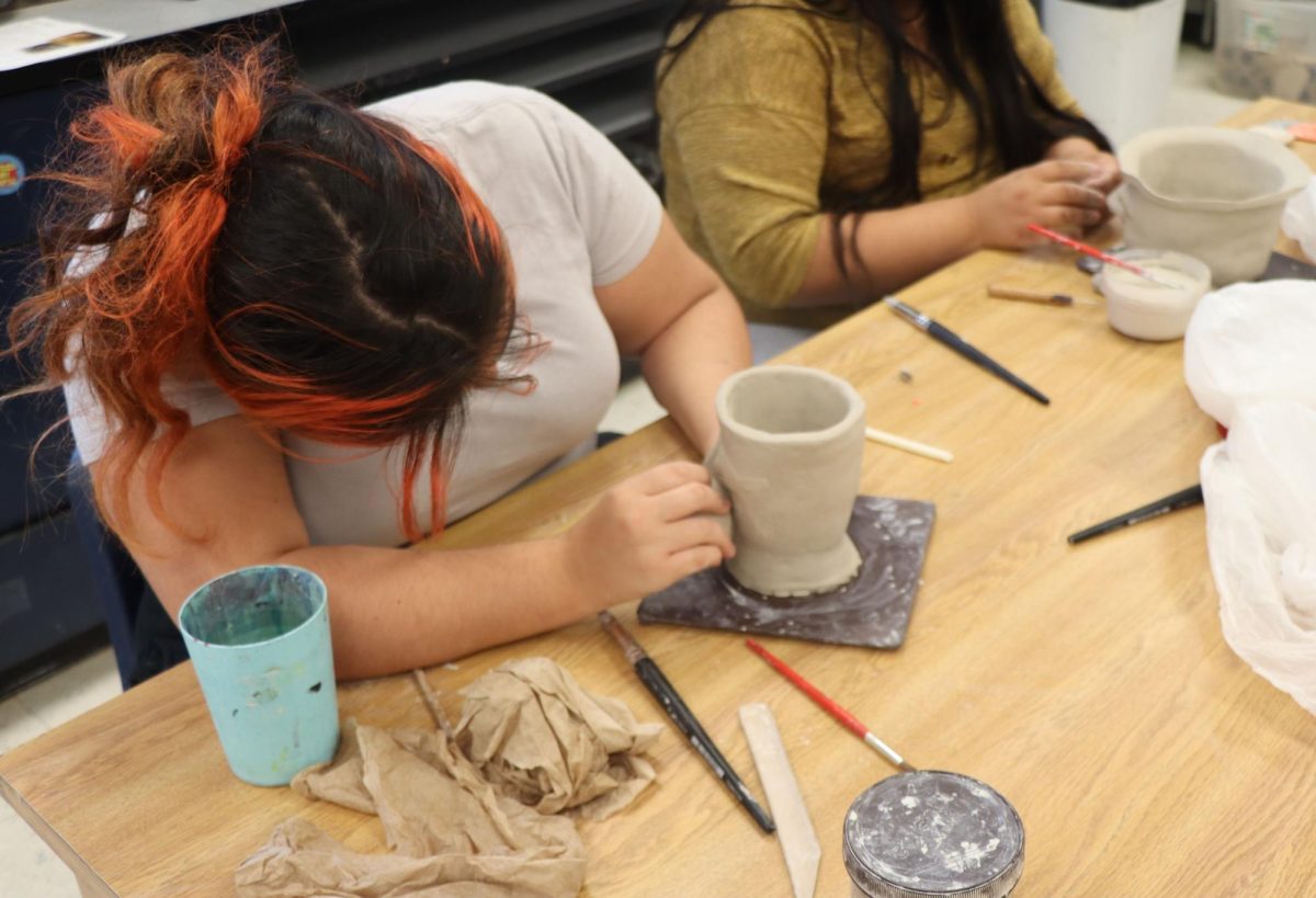 Student independently working on pottery art project.