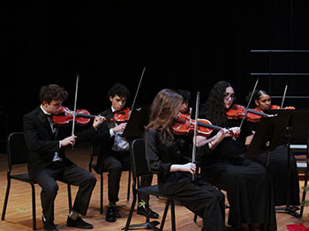 A group of violinists are playing the soundtrack of the season.