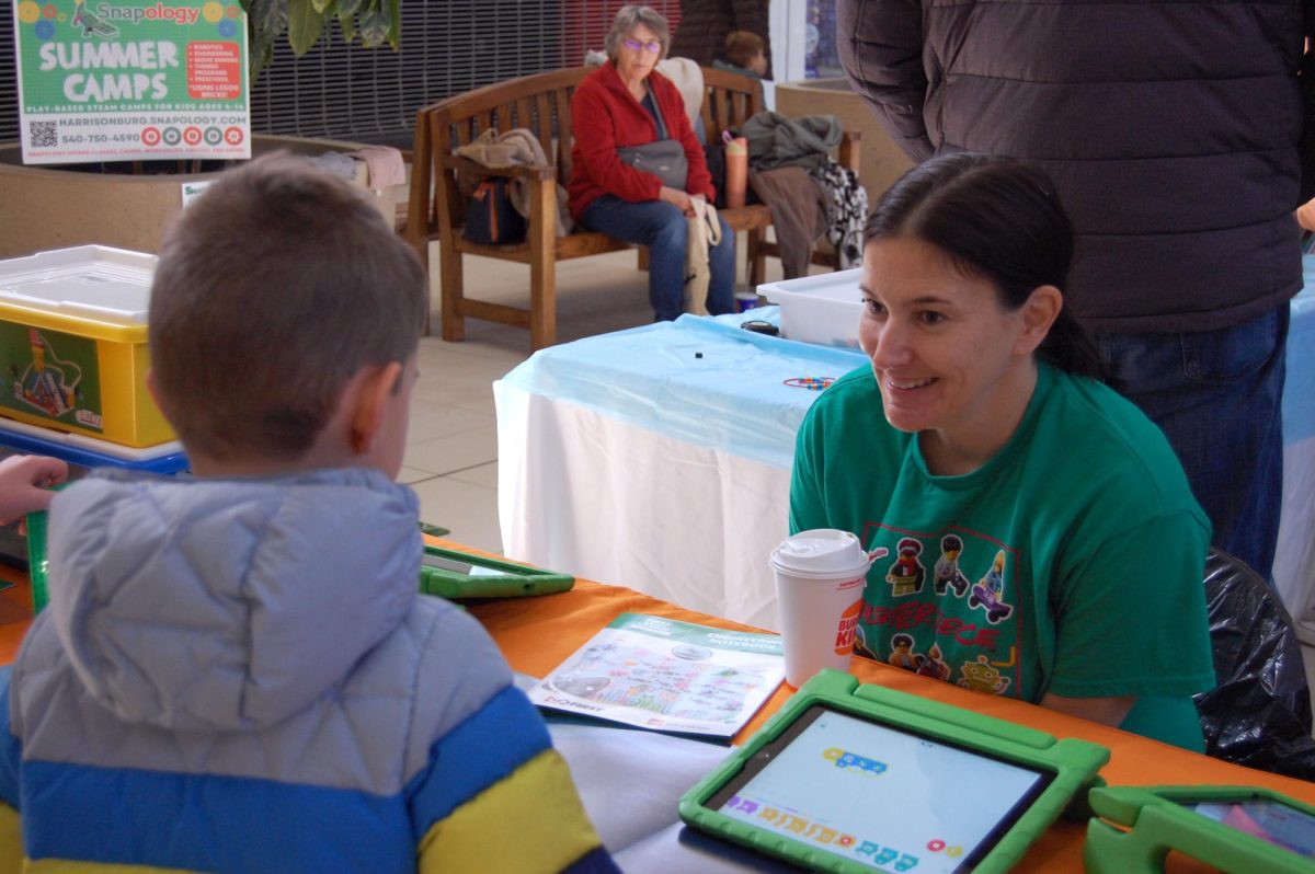 STEM adult helps with creative booth for students.