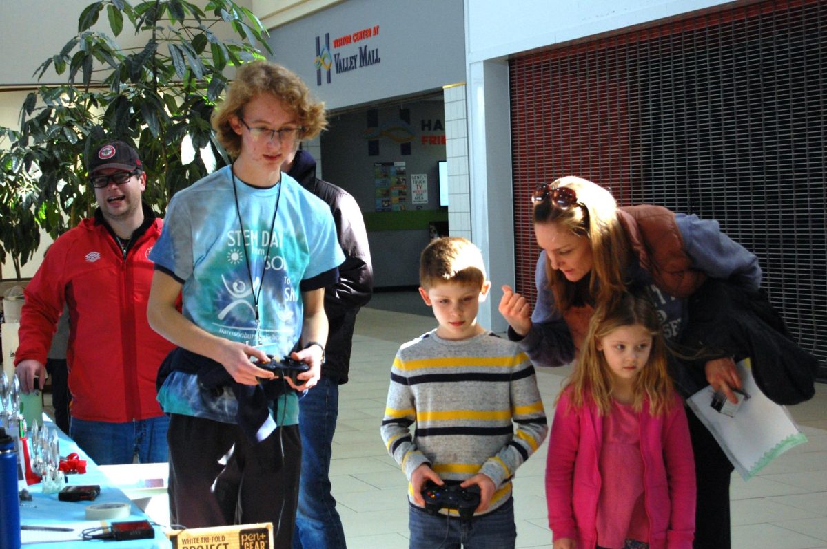 Sophomore Lewis Johnson helps stem enthusiast drive robot.