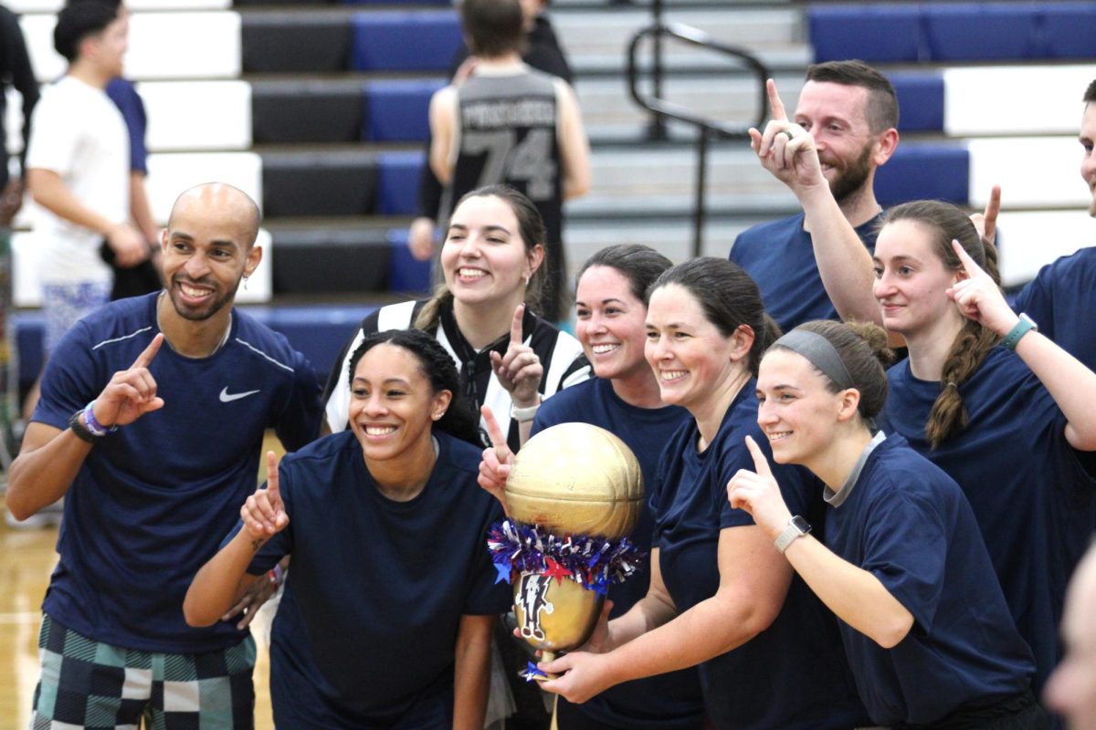 Staff pose with trophy after winning the student vs staff game.