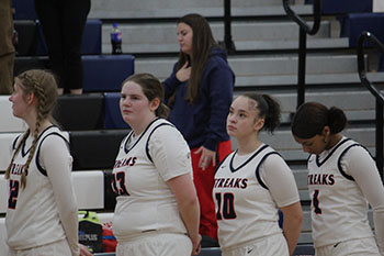 The girls are doing the pledge of allegiance before the game starts.