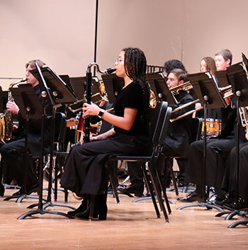 Students in the back play their woodwind instruments.