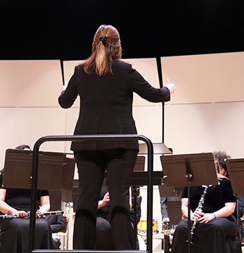 The conductor leads the band through their song.