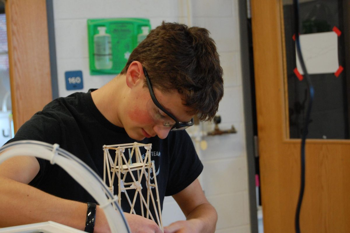 Sophomore Josiah Nafziger attaches the weights to his team's tower.