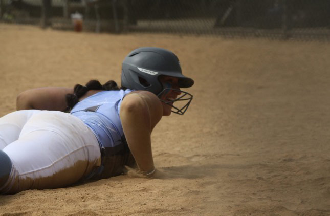 Senior Kayli Alvarado sliding into the dirt at home plate.