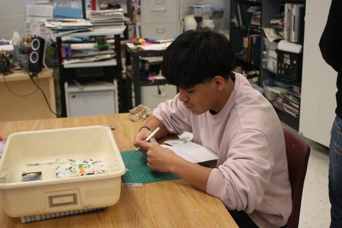 Student cutting out paper in Art.