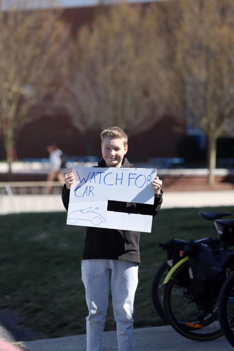 Junior Vincent Rhodes holds up a sign warning of oncoming cars.