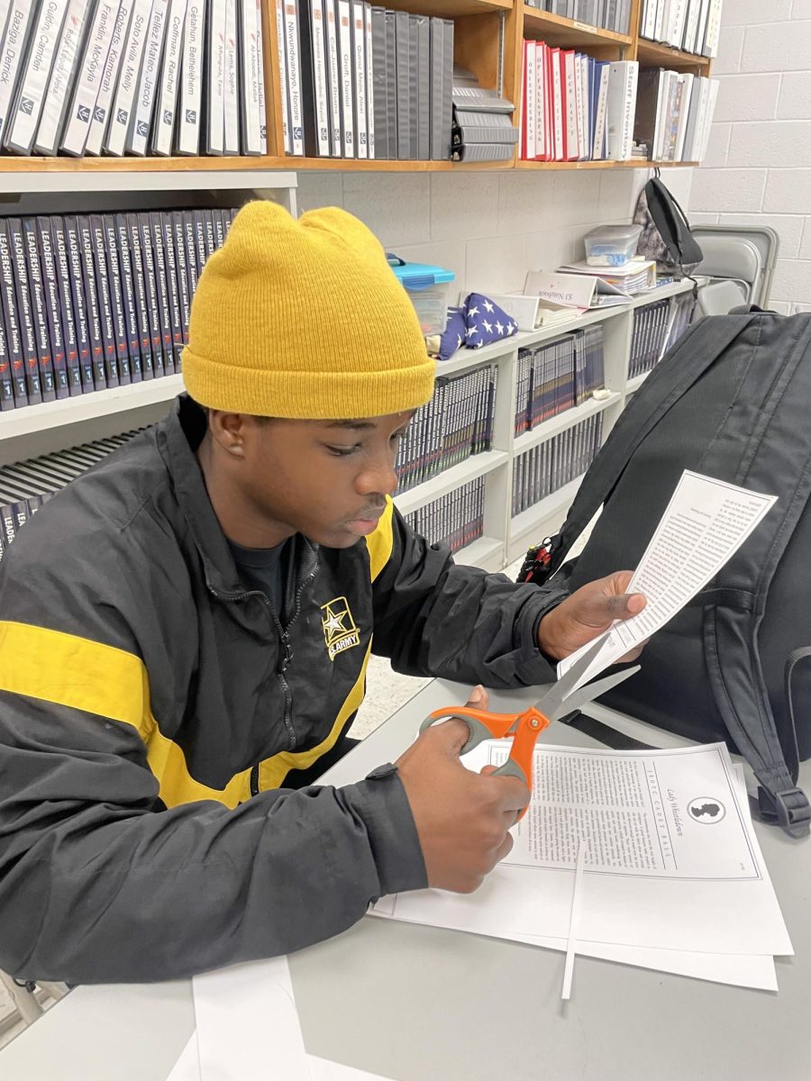 Sophmore Derrick Bazinga works on cutting the ball entrance tickets.