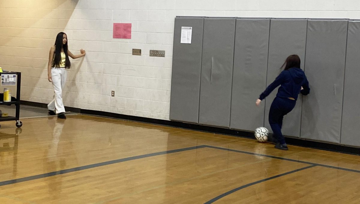 Two freshman pass the soccer ball.