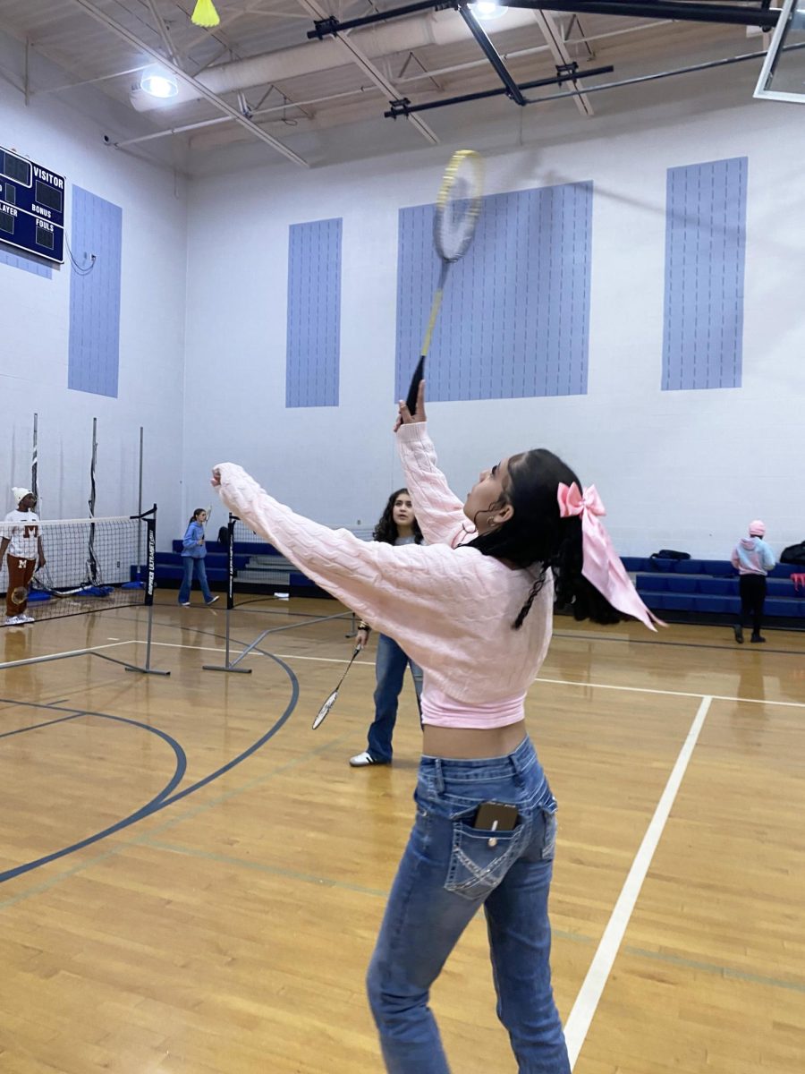 Freshman serves in badminton unit.