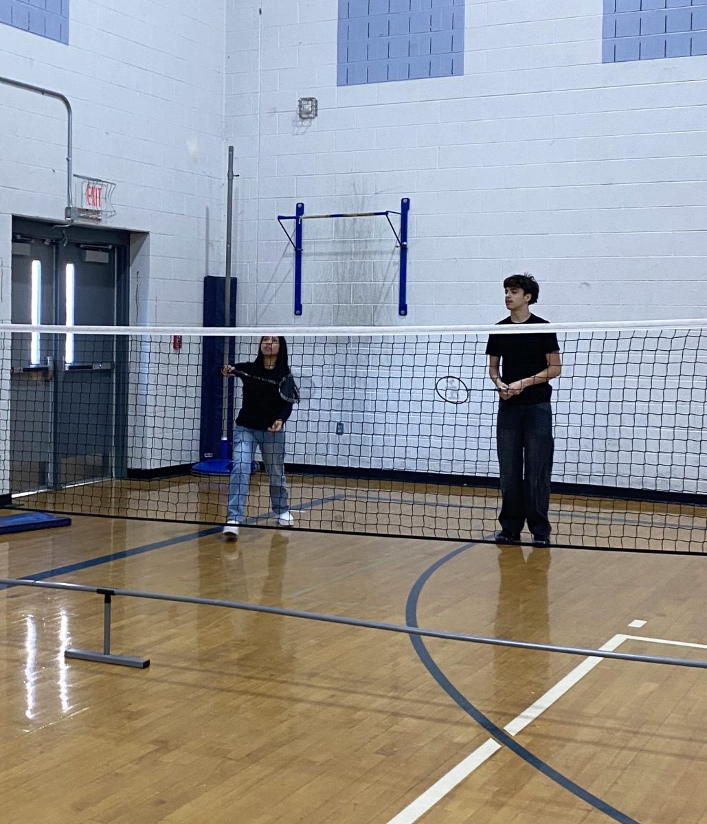 Two freshman play against their friends in a game of badminton.