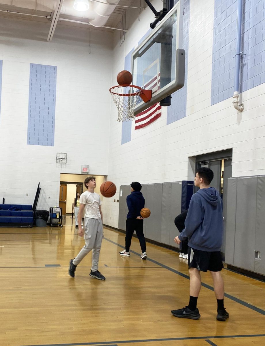 Two freshman play basketball with each other and practice their lay-ups.