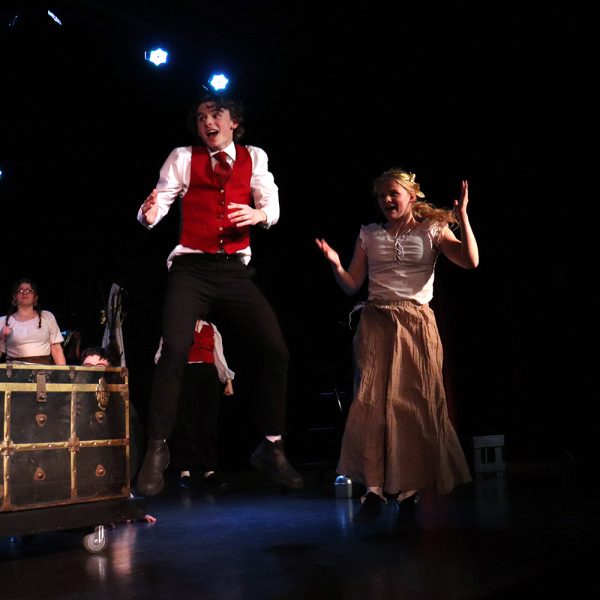 Louis Gibson as Louis De Rougemont, Madison Keller as Yamba, and in the background, Claire Keller and Hazel Pinnow as Ensemble.